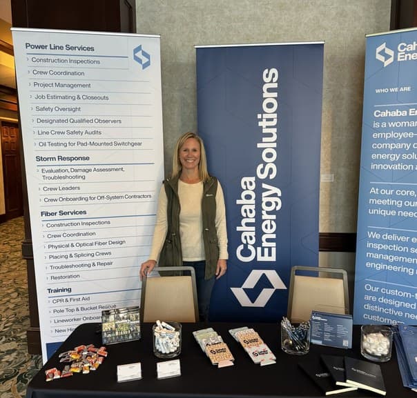 Brandi Vines at the Cahaba Energy Solutions booth, between banners describing the company's power-line and fiber services.